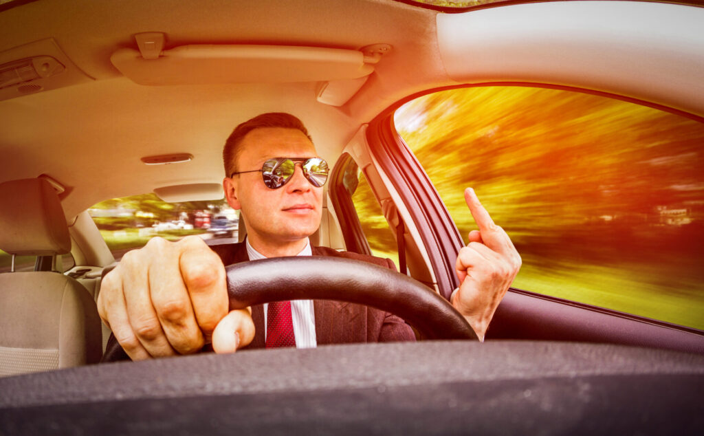 header image for are people in connecticut rude. a man driving a car and putting his middle finger up.