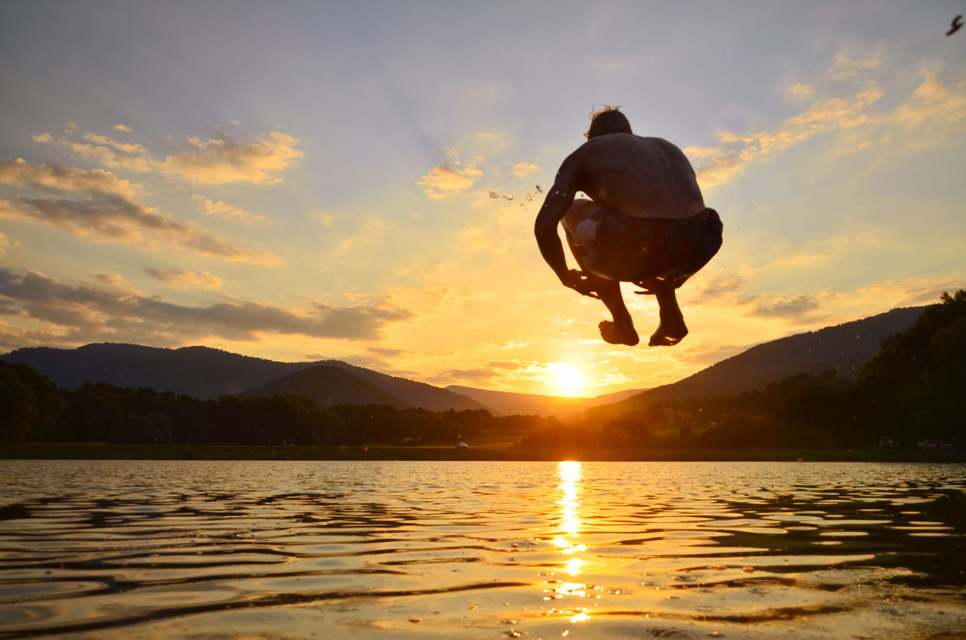 image of a man jumping in to a lake from a cliff jumping spot in ct.