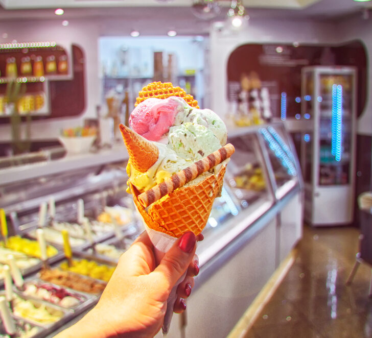 image of hand holding cone with the best ice cream in CT in it. Colorful and fancy background.