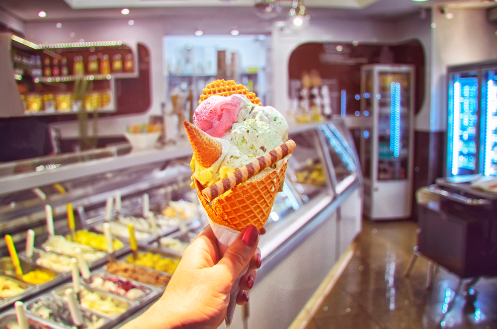 image of hand holding cone with the best ice cream in CT in it. Colorful and fancy background.